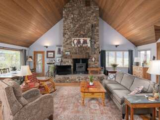 Step into rustic elegance with this stunning living room, featuring a grand stone fireplace and vaulted wooden ceilings.