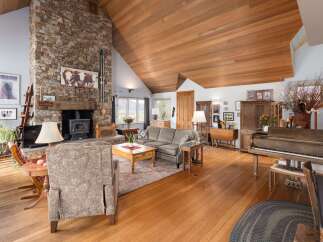 This stunning living room boasts a rustic charm with its stone fireplace and wooden ceiling.