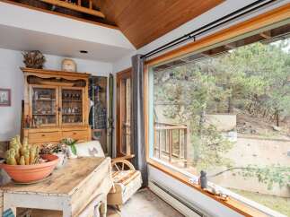 This charming property boasts a cozy interior with a rustic wooden table and a cabinet filled with vintage decor.