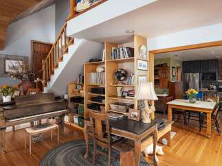 This charming home features a cozy living space with a grand piano and a built-in bookshelf, perfect for relaxation and entertainment.
