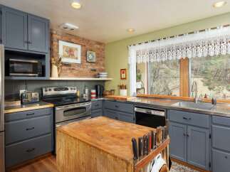 This charming kitchen boasts a rustic aesthetic with its exposed brick wall and wooden butcher block island.