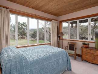 This charming bedroom offers a serene retreat with its natural light and scenic views.