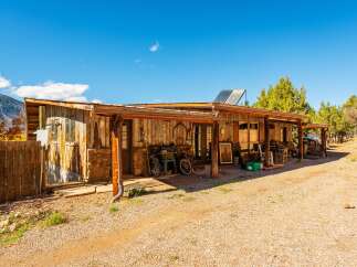 This charming property features a rustic cabin with a covered porch, perfect for enjoying the outdoors.