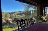 Enjoy breathtaking mountain views from this dining area, featuring a large window overlooking lush greenery and rolling hills.