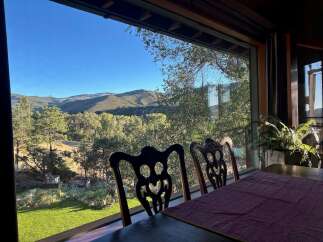 Enjoy breathtaking mountain views from this dining area, featuring a large window overlooking lush greenery and rolling hills.