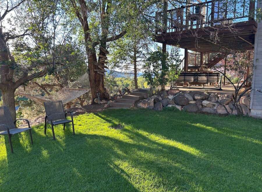 Enjoy the serene outdoors with this property's inviting backyard oasis, featuring a comfortable hammock strung between mature trees and two classic patio chairs perfect for relaxation.