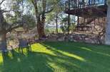 Enjoy the serene outdoors with this property's inviting backyard oasis, featuring a comfortable hammock strung between mature trees and two classic patio chairs perfect for relaxation.
