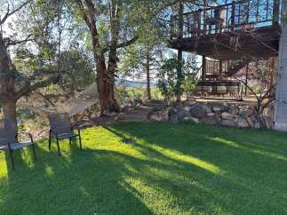 Enjoy the serene outdoors with this property's inviting backyard oasis, featuring a comfortable hammock strung between mature trees and two classic patio chairs perfect for relaxation.