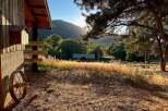 Experience rustic charm with this property featuring a wooden cabin nestled amidst lush greenery and rolling hills.