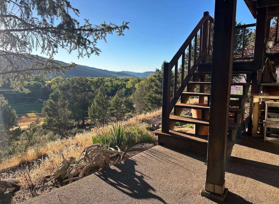 Experience breathtaking mountain views from this unique property, featuring a charming wooden staircase leading to an elevated deck.