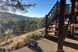 Experience breathtaking mountain views from this unique property, featuring a charming wooden staircase leading to an elevated deck.