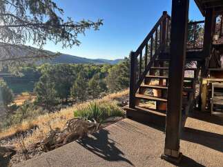 Experience breathtaking mountain views from this unique property, featuring a charming wooden staircase leading to an elevated deck.
