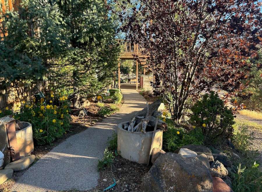 Discover a charming pathway leading to a rustic wooden pergola, perfect for outdoor gatherings.
