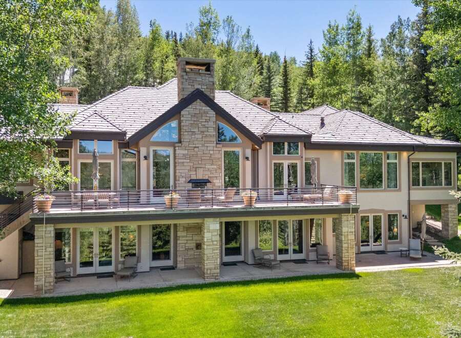 Experience luxury mountain living in this stunning estate, featuring a grand stone facade and expansive windows that capture breathtaking forest views.