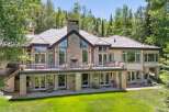 Experience luxury mountain living in this stunning estate, featuring a grand stone facade and expansive windows that capture breathtaking forest views.