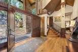 Step into a grand entryway featuring a stunning double door opening to a stone staircase and lush greenery.
