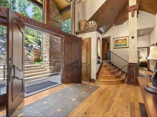 Step into a grand entryway featuring a stunning double door opening to a stone staircase and lush greenery.
