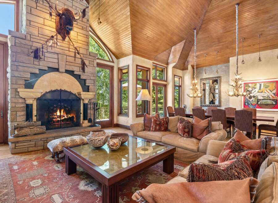Experience rustic luxury in this stunning living room, featuring a grand stone fireplace with a mounted bison head and a cozy seating area perfect for gathering.