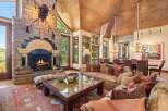 Experience rustic luxury in this stunning living room, featuring a grand stone fireplace with a mounted bison head and a cozy seating area perfect for gathering.