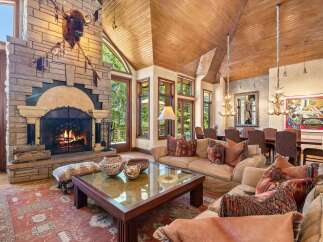 Experience rustic luxury in this stunning living room, featuring a grand stone fireplace with a mounted bison head and a cozy seating area perfect for gathering.