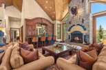 Experience rustic luxury in this grand living room, featuring a stunning stone fireplace with a mounted bison head and a full-service wooden bar with leather stools.