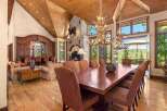 Experience luxurious mountain living in this grand dining room, featuring a massive stone fireplace and a rustic antler chandelier.
