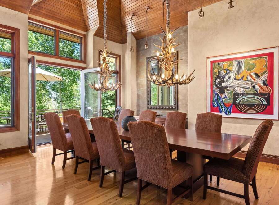 Experience elegant dining in this spacious room featuring a large wooden table surrounded by upholstered chairs.