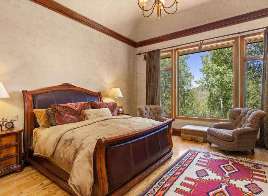 Experience luxurious mountain living in this stunning bedroom, featuring a grand leather-trimmed bed and plush bedding.