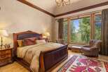 Experience luxurious mountain living in this stunning bedroom, featuring a grand leather-trimmed bed and plush bedding.