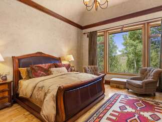 Experience luxurious mountain living in this stunning bedroom, featuring a grand leather-trimmed bed and plush bedding.
