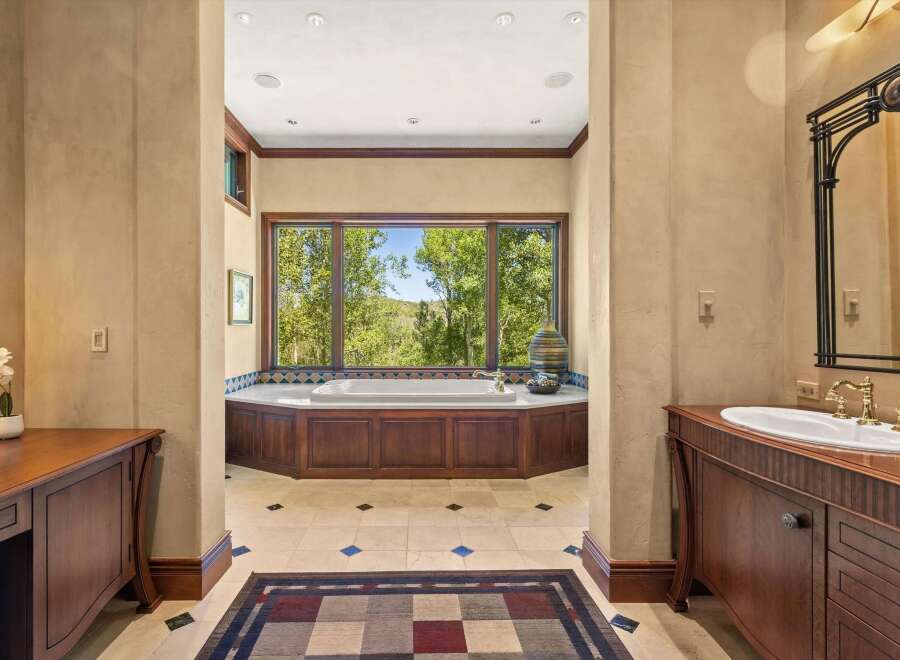 Indulge in luxury with this stunning bathroom featuring a spacious soaking tub set against a backdrop of breathtaking natural views.