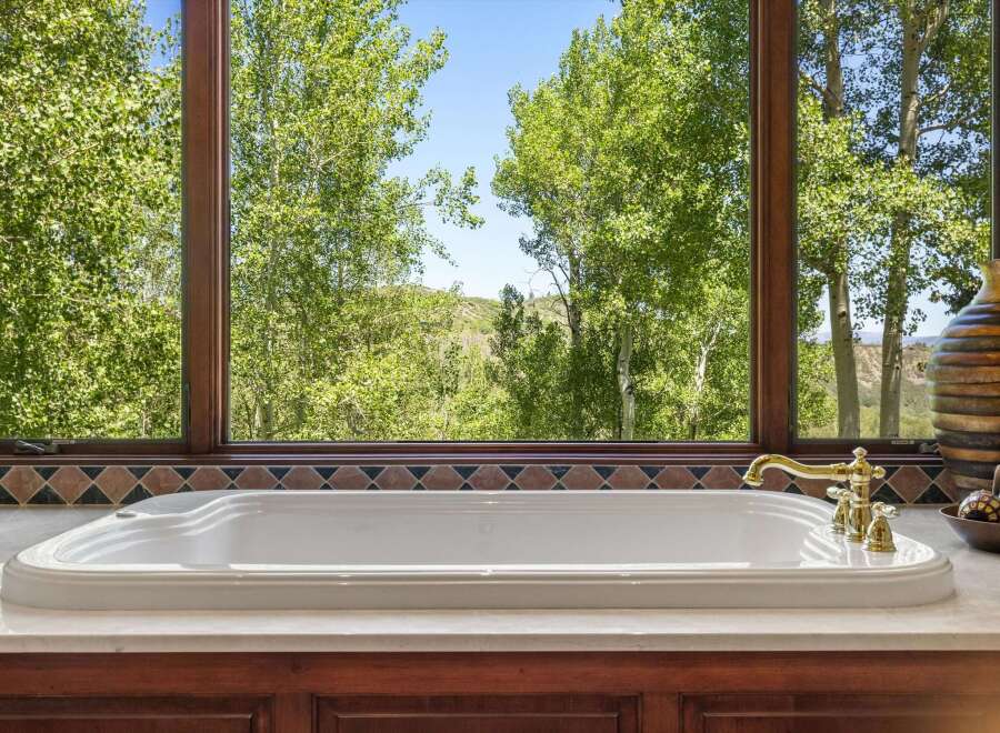 Indulge in ultimate relaxation with this luxurious soaking tub, perfectly positioned to offer breathtaking views of the surrounding lush greenery and rolling hills.