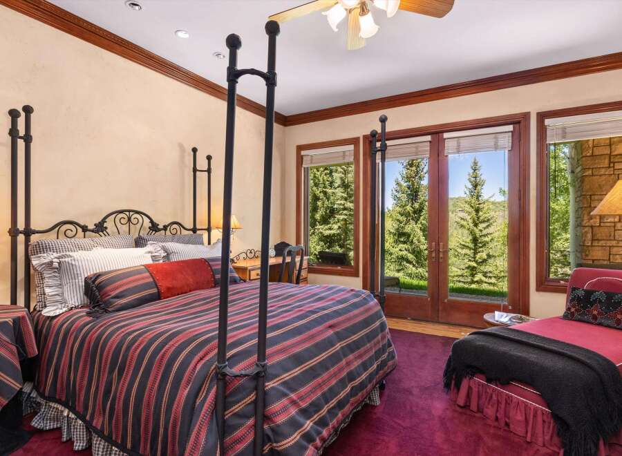Experience luxurious mountain living in this stunning bedroom, featuring a grand four-poster bed adorned with elegant striped bedding.
