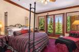 Experience luxurious mountain living in this stunning bedroom, featuring a grand four-poster bed adorned with elegant striped bedding.