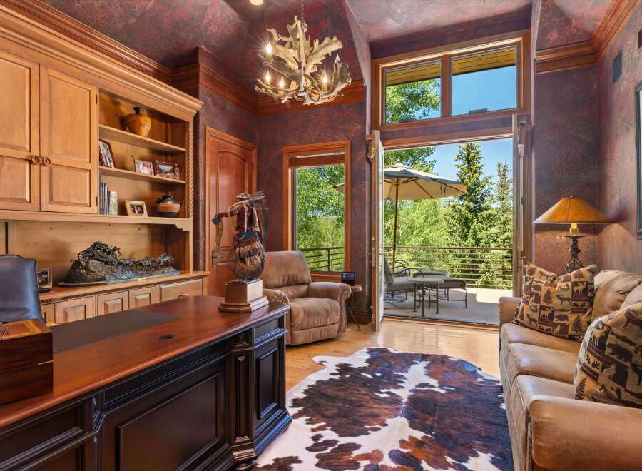 This luxurious office space features a large wooden desk, built-in shelving, and a comfortable recliner, perfect for a home office.