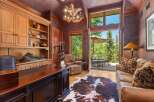 This luxurious office space features a large wooden desk, built-in shelving, and a comfortable recliner, perfect for a home office.