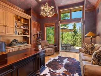This luxurious office space features a large wooden desk, built-in shelving, and a comfortable recliner, perfect for a home office.