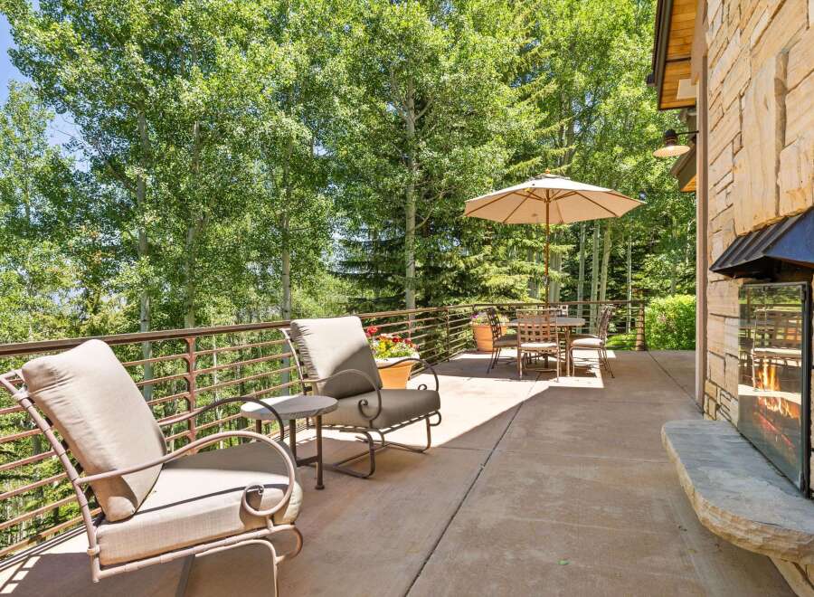 Enjoy the serene mountain views from this expansive outdoor living space, complete with comfortable seating and a dining area under a large umbrella.