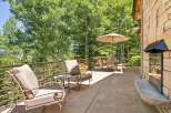 Enjoy the serene mountain views from this expansive outdoor living space, complete with comfortable seating and a dining area under a large umbrella.
