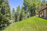Experience the beauty of nature with this stunning property, featuring a lush green lawn that slopes gently towards a serene wooded area.