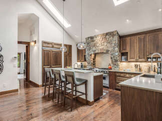 Step into luxury with this stunning kitchen, boasting a rustic stone range hood and custom cabinetry.