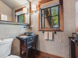This charming bathroom features a unique, rustic design with a vintage vanity and a stylish sink.