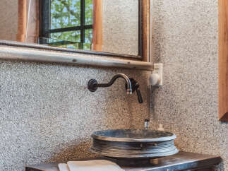 This unique bathroom features a rustic vanity with a vintage sink and faucet.