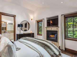 Experience luxury in this stunning bedroom featuring a cozy fireplace and a large flat-screen TV, perfect for relaxing evenings.