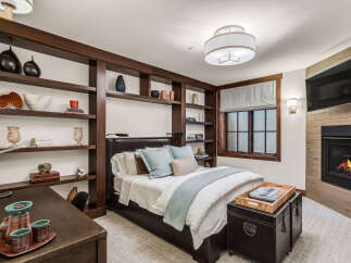 This luxurious bedroom boasts a cozy fireplace and a built-in bookshelf, perfect for relaxing evenings.