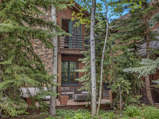 Nestled amidst lush greenery, this stunning property boasts a charming exterior with a stone facade and wooden accents.