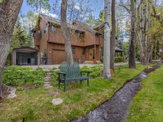 Nestled in a serene natural setting, this stunning property boasts a beautiful wooden exterior and a charming green bench.