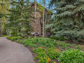 Nestled amidst lush greenery, this stunning property boasts a unique stone facade and a charming wooden exterior.
