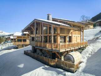 Experience luxury living in this stunning wooden chalet nestled in a snowy mountain landscape.