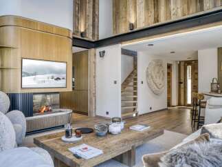 Experience luxury living in this stunning chalet, featuring a cozy fireplace and a modern TV setup.